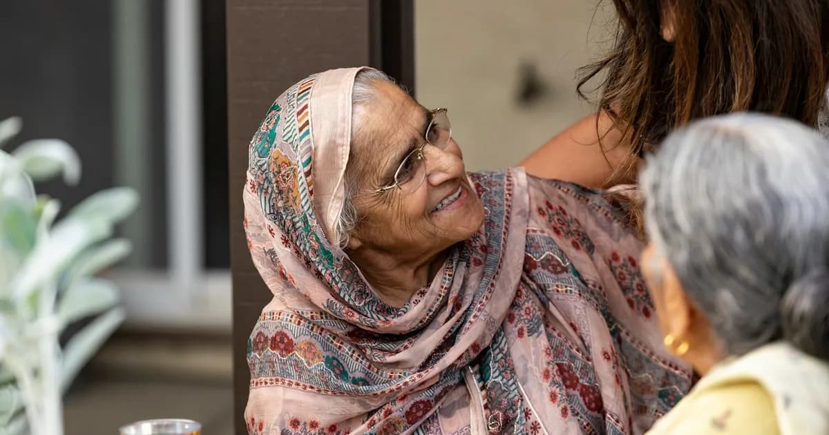 An older South Asian woman speaking with a younger family member in a warm home setting