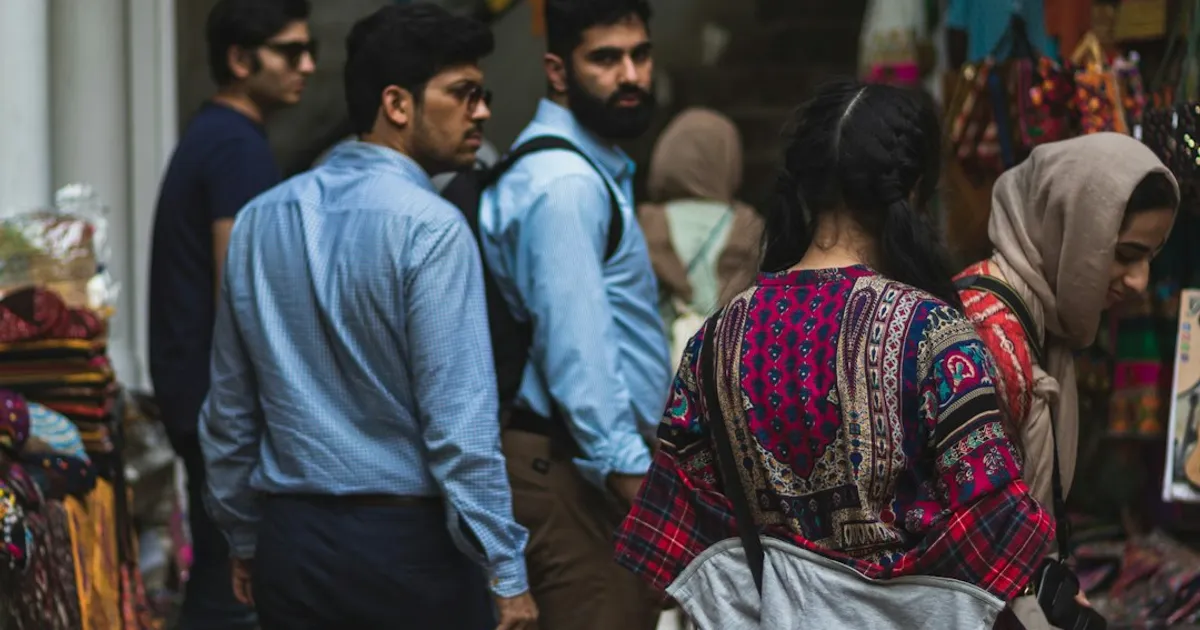 A group of people standing outside a small, brightly lit shop in a South Asian market