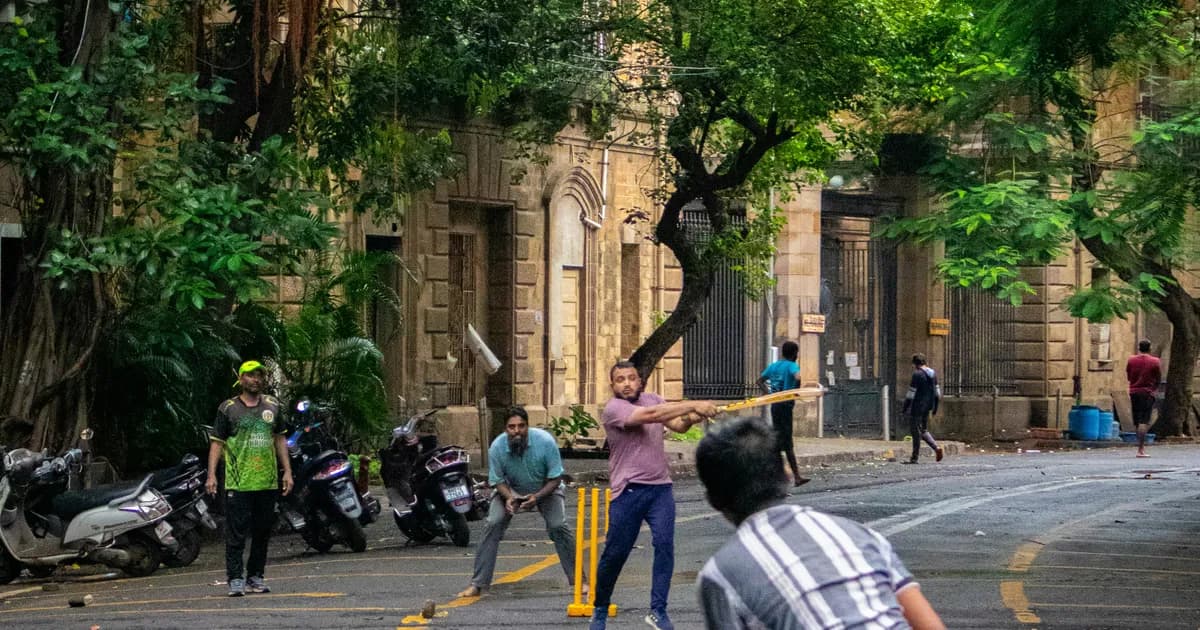 Children playing cricket in a South Asian street at sunset
