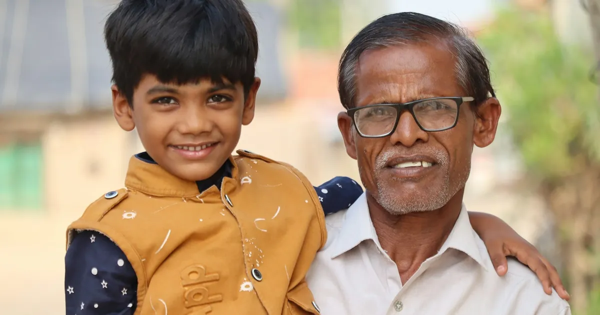 A South Asian elder and a young relative smiling together during a home visit
