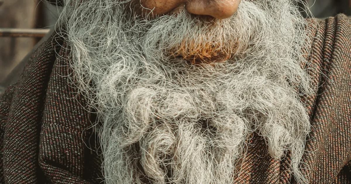 A South Asian grandfather with a white beard reflecting on memories