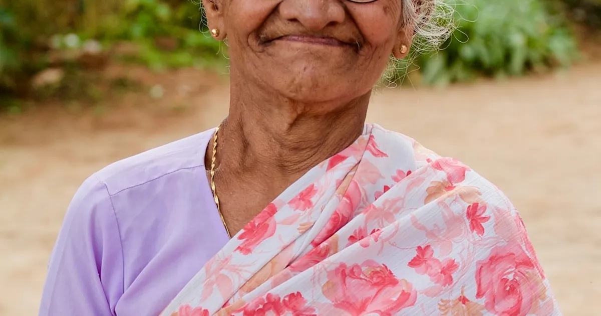 An elderly South Asian grandmother wearing a floral dupatta holding an heirloom book