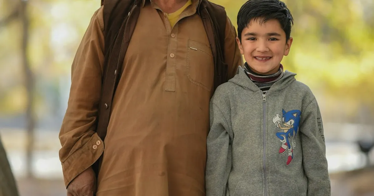 An elderly Pakistani man and a young boy standing together outdoors, representing the generational connections at the heart of a South Asian family tree