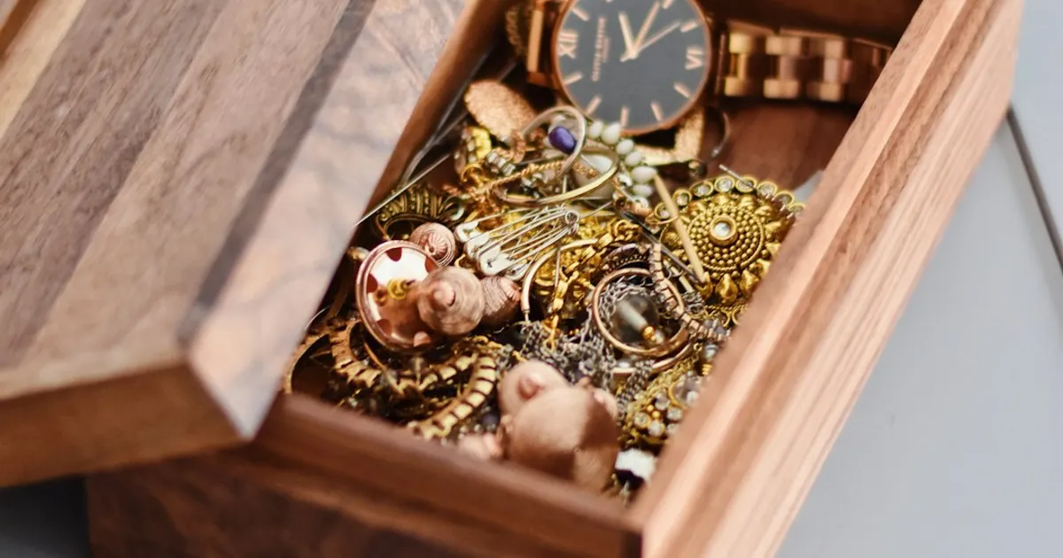 A gold watch and pendant resting on a wooden box, representing a family heirloom passed down through generations