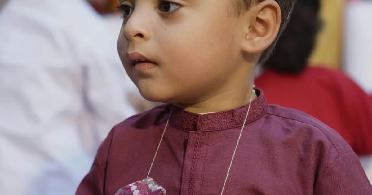 A young boy in traditional South Asian clothing with flower garlands, celebrating a family milestone