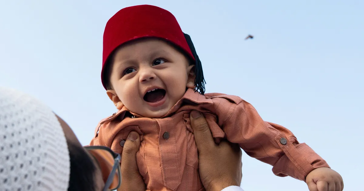 Father holding his baby son outside a mosque, capturing the beauty of Eid family traditions and intergenerational connection